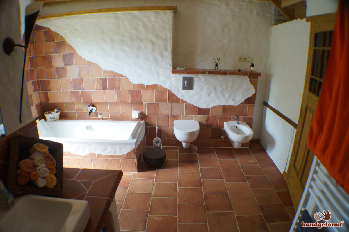 Kreativer Einsatz von Terracotta-Fliesen an Wand, Ofen und Dusche