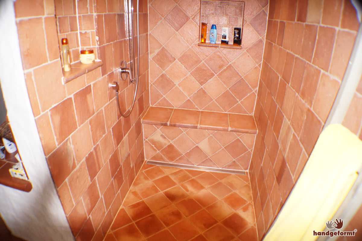 Kreativer Einsatz von Terracotta-Fliesen an Wand, Ofen und Dusche