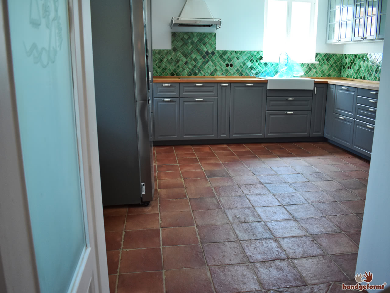 Die Küche kurz vor ihrer Fertigstellung. Grüne Wandfliesen und Bodenfliesen aus Terracotta ergänzen sich gut.