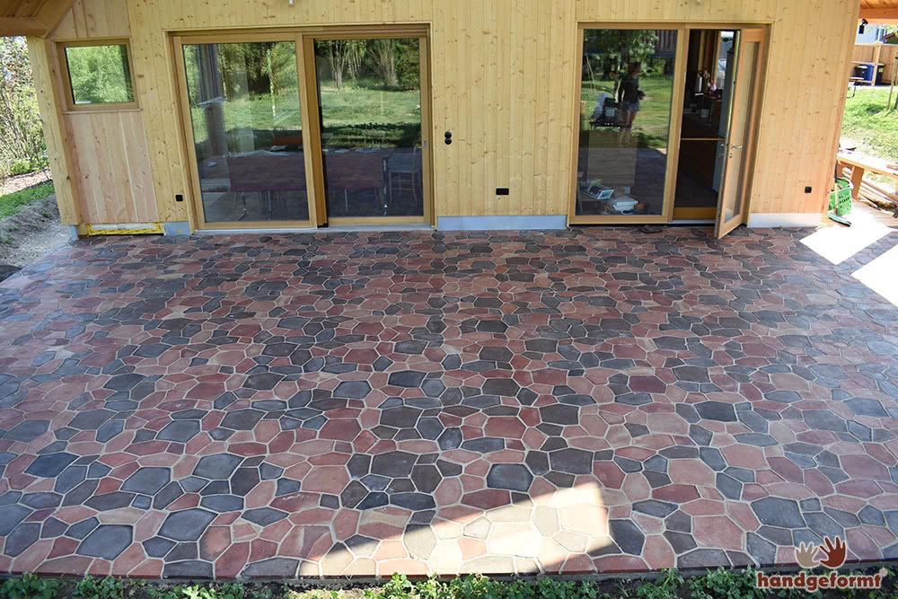 Terrasse aus individuellen Mosaikfliesen hinter dem Holzhaus von Sarah Wiener