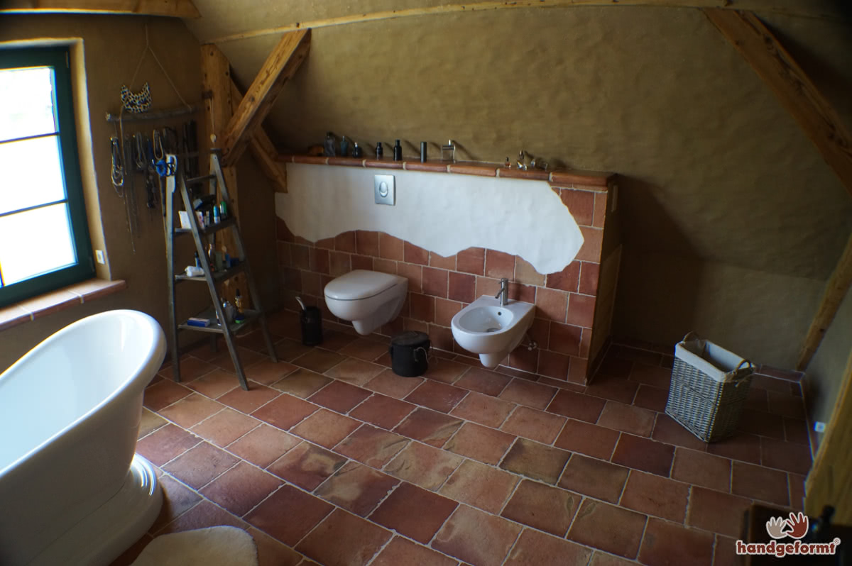 Kreativer Einsatz von Terracotta-Fliesen an Wand, Ofen und Dusche